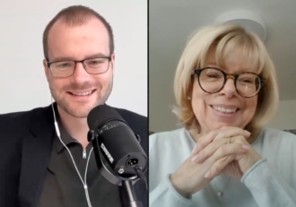 Split-screen video call with a man on the left and a woman on the right, both smiling; man wears glasses and a microphone, woman wears glasses and clasped hands.