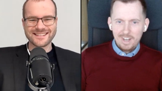 Split-screen video interview: left man wearing glasses speaks into a microphone; right man in a burgundy sweater wears wireless earbuds.