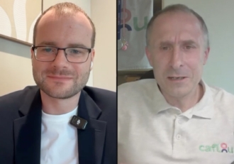 Split-screen video call showing two men: left is wearing glasses and a blazer with a clip-on mic; right is in a light polo shirt with a logo.